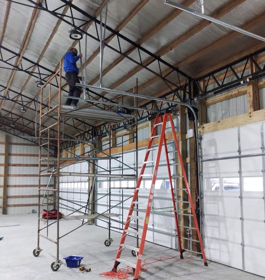 Garage door installation Clarksville TN technician on scaffold working on commercial door