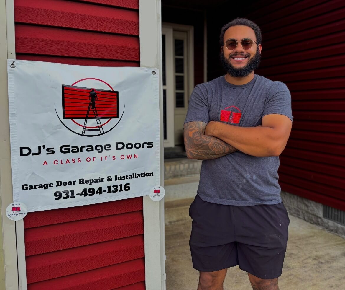 Owner sitting next to business banner for garage door services Clarksville